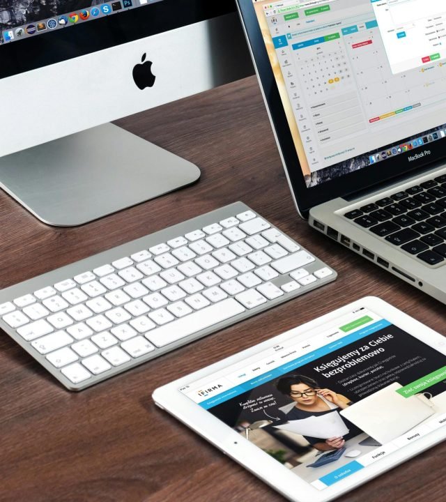 A sleek office desk setup featuring Apple devices: iMac, MacBook, and iPad.