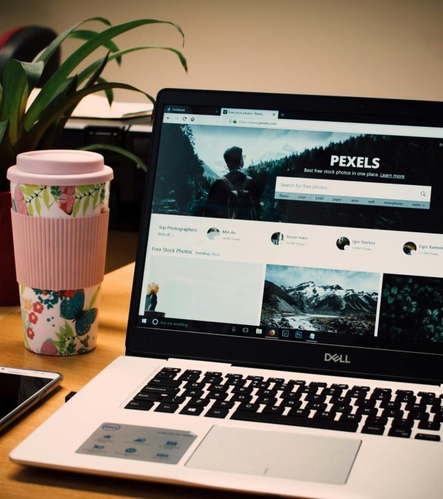 A tidy desk setting with a laptop showing a stock photo website and a smartphone.